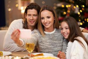 Beautiful family celebrating Christmas at home and taking selfie photo