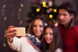 hermosa familia celebrando la navidad en casa y tomando selfie foto