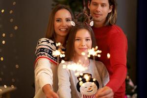 Beautiful family celebrating Christmas and holding sparklers photo