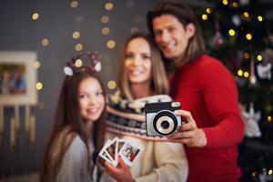 Beautiful family celebrating Christmas at home and taking instant pictures photo