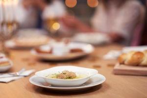 cena de janucá. familia reunida alrededor de la mesa con platos tradicionales foto