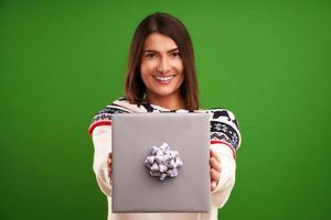 Mujer adulta feliz con regalo de navidad sobre fondo verde foto