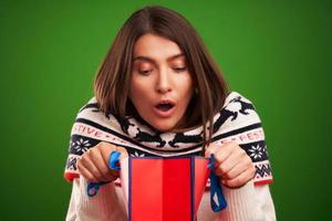 Adult happy woman with Christmas gift over green background photo