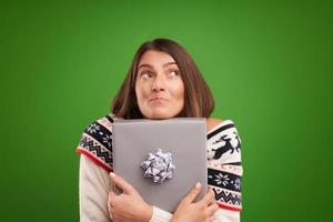 Adult happy woman with Christmas gift over green background photo