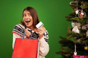 Adult happy woman shopping for Christmas presents over green background photo