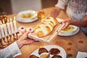 Hanukkah dinner. Family gathered around the table sharing challah photo