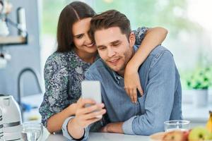 pareja en la cocina de casa usando un teléfono inteligente foto