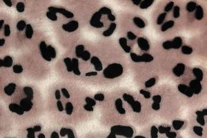 Close-up pattern of fleece fabric with leopard pattern. Brown-beige and black striped repeating on the surface of fur clothes, abstract texture background. photo