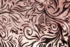 Close-up pattern of fleece fabric with leopard pattern. Brown-beige and black striped repeating on the surface of fur clothes, abstract texture background. photo