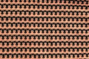 The background of a knitted fabric is orange-black with a regular geometric pattern. Openwork finely knitted woolen fabric. photo