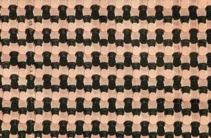 The background of a knitted fabric is orange-black with a regular geometric pattern. Openwork finely knitted woolen fabric. photo