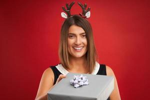 Adult happy woman with Christmas gift over red background photo