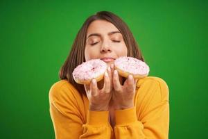Beautiful woman posing with donuts over green background photo