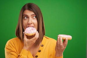 Beautiful woman posing with donuts over green background photo