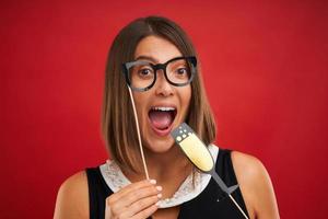 Attractive brunette woman posing with New Year photo gadgets over red background