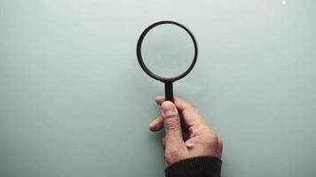 Man holds magnifying glass on blank background video