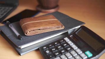 Laptop on home desk with calculator notebook wallet and plant video