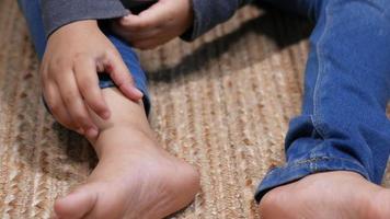 enfant assis se gratte la cheville et pieds nus video