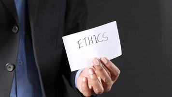 Man in business suit holds up card with ETHICS written on it video