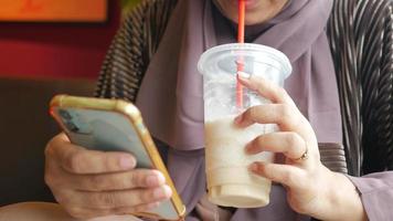 vrouw drinken een milkshake en op zoek Bij smartphone video