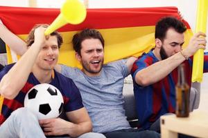 Happy male friends cheering and watching sports on tv photo