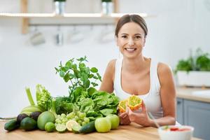 mujer adulta sana con comida verde en la cocina foto