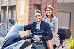 Happy mature couple riding a scooter in the city on a sunny day photo