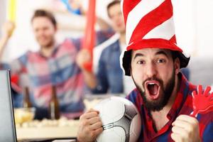 Happy male friends cheering and watching sports on tv photo