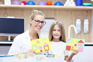 Child psychologist working with young girl in office photo