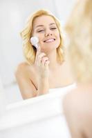 Woman using face cleansing brush photo