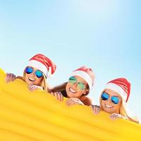 Group of girls in Santa's hats having fun on the beach photo