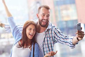 Happy couple using smartphone in city in rainy day photo