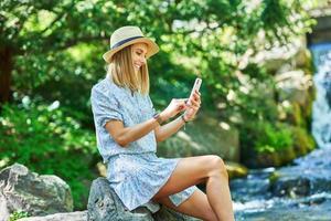 A nice girl sitting on a rock with smartphone photo