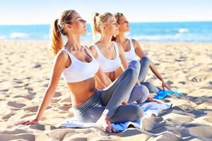 Group of women practising yoga on the beach photo