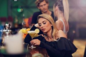 Young woman sitting alone in bar with a coctail photo