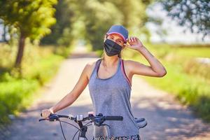 mujer joven en bicicleta en el campo con una máscara foto