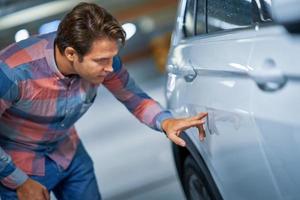 Portrait of adult man with scratched car at underground parking lot photo