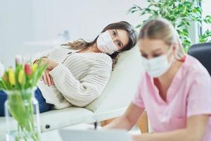 Professional psychiatrist consulting her patient and making notes both in masks photo
