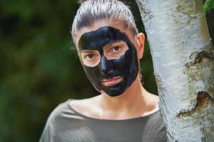Young woman in nature with black mask on face photo