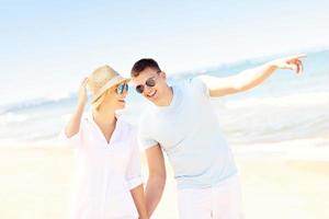 Cheerful couple walking along the beach photo