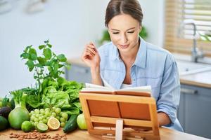 mujer adulta sana con comida verde en la cocina foto