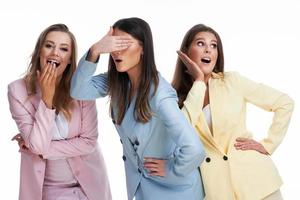 Three women in pastel suits posing over white background photo