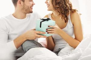 Young couple with present in bed photo