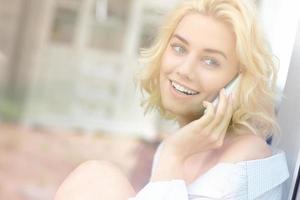 mujer bonita joven sentada en la ventana y hablando por teléfono foto