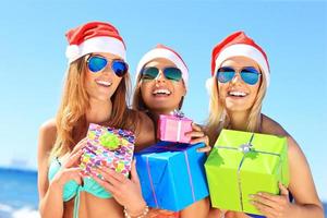 grupo de chicas con sombreros de santa divirtiéndose en la playa foto