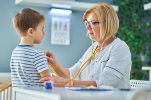 Pediatrician doctor examining little kids in clinic photo