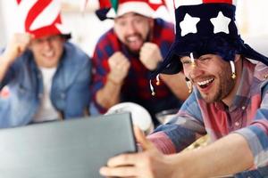 Happy male friends cheering and watching sports on tv photo