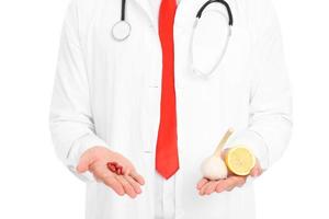 Midsection of doctor holding pills and lemon with garlic photo