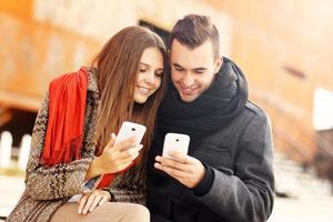 Romantic couple using smart phones during autumn walk photo