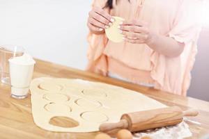 Young woman trying to make pierogi in kitchen photo